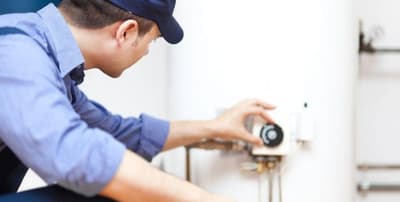 termoidrauilo con berretto nero e camicia celeste controlla il termostato al muro
